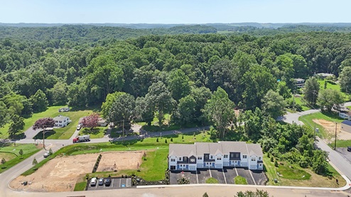 A drone aerial view of the a 7 unit townhome building and adjacent parking lot