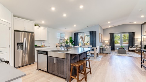 Kitchen with shaker cabinets, quartz counters, stainless steel appliances, pantry, and an island with a breakfast bar