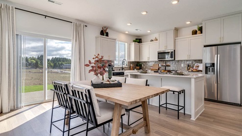 Kitchen with shaker cabinets, quartz counters, stainless steel appliances, pantry, and an island with a breakfast bar