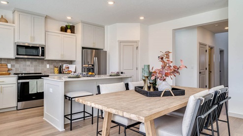 Kitchen with shaker cabinets, quartz counters, stainless steel appliances, pantry, and an island with a breakfast bar