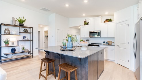 Kitchen with shaker cabinets, quartz counters, stainless steel appliances, pantry, and an island with a breakfast bar