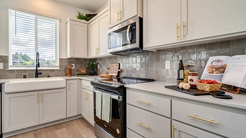 Kitchen with shaker cabinets, quartz counters, stainless steel appliances, pantry, and an island with a breakfast bar