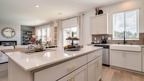 Kitchen with shaker cabinets, quartz counters, stainless steel appliances, pantry, and an island with a breakfast bar