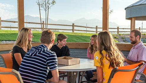 A family sitting at a table together outside at a D.R. Horton community.