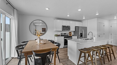 Focusing on the kitchen and dining room there is a large island with sink, white shaker cabinets and stainless steel appliances.