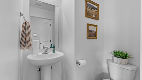 On the other side of the kitchen opposite the dining room and towards the garage entrance is the powder room with a pedestal sink.