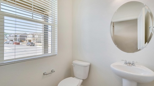 half bath with a window, a mirror and toilet