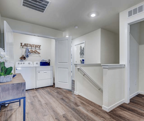 spacious hallway with view of stairs and laundry room