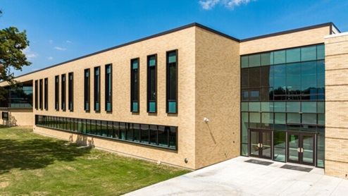 JJ Pearce High School building in Richardson, Texas, featuring a large parking lot and school signage