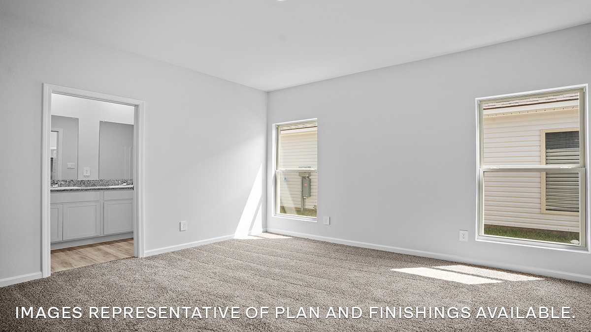 Large primary bedroom with dual windows overlooking the backyard