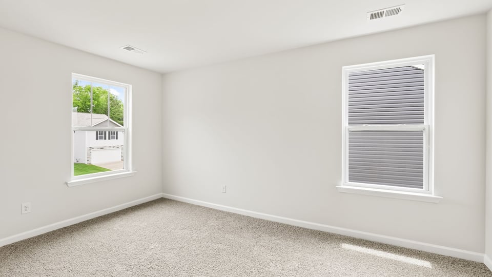 Primary bedroom with carpet and windows.