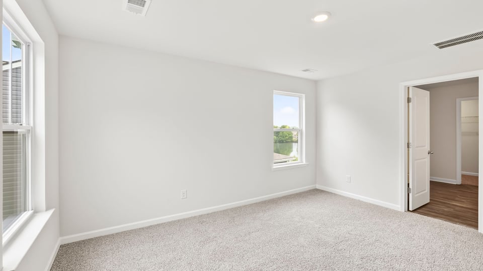 Primary bedroom with carpet and windows.