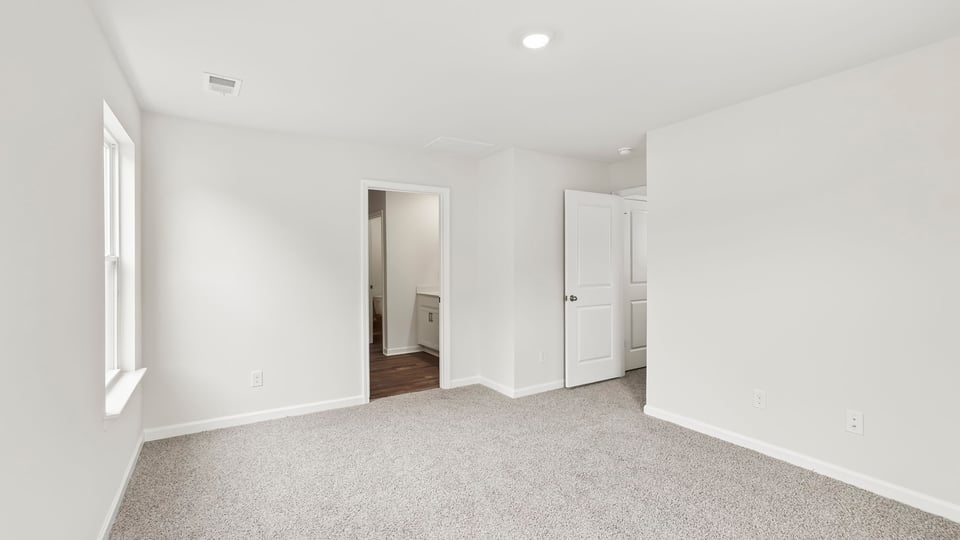 Primary bedroom with carpet and windows.