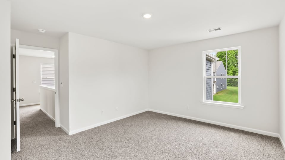Primary bedroom with carpet and windows.
