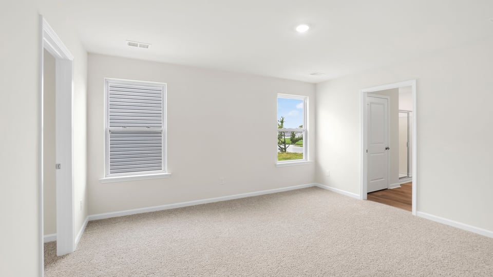 Primary bedroom with carpet and window.
