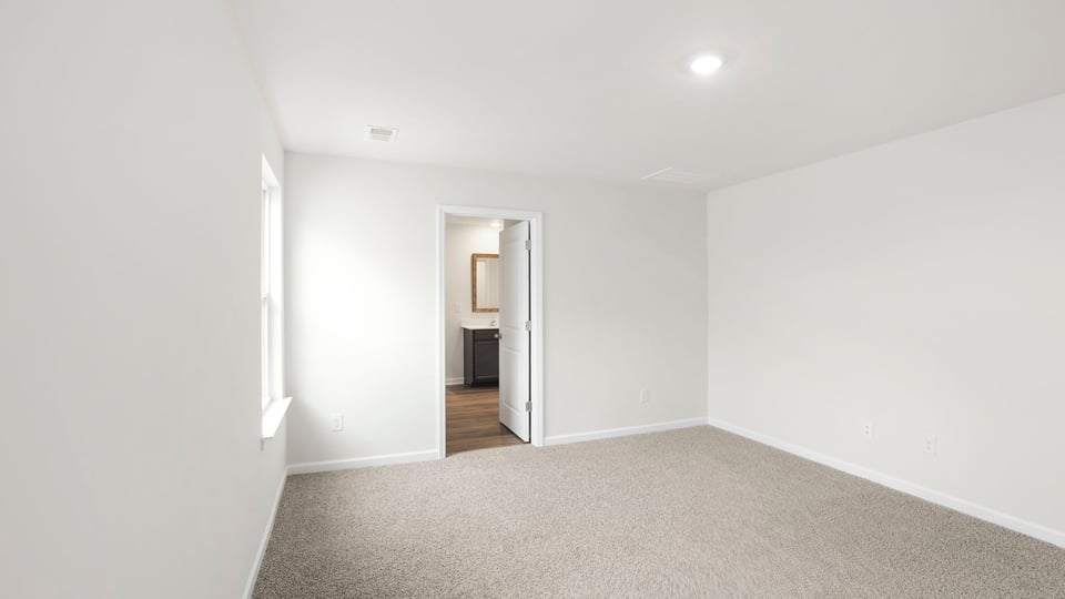 Primary bedroom with carpet and window.