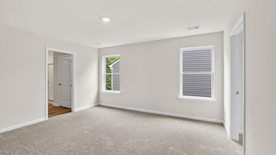 Primary bedroom with carpet and windows.
