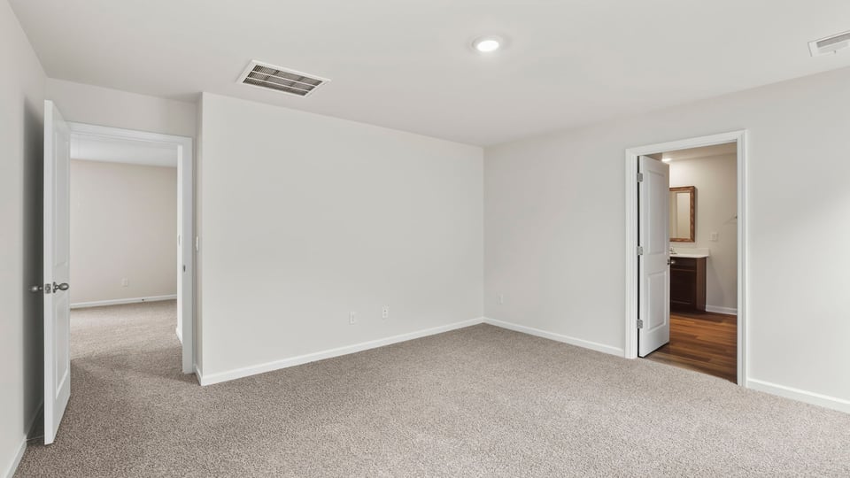 Primary bedroom with carpet and windows.