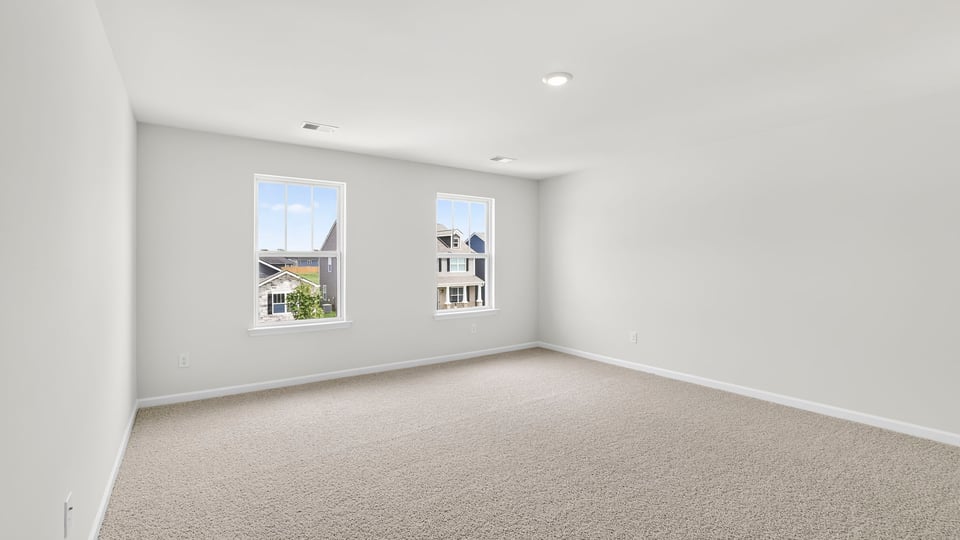 Primary bedroom with carpet and window.
