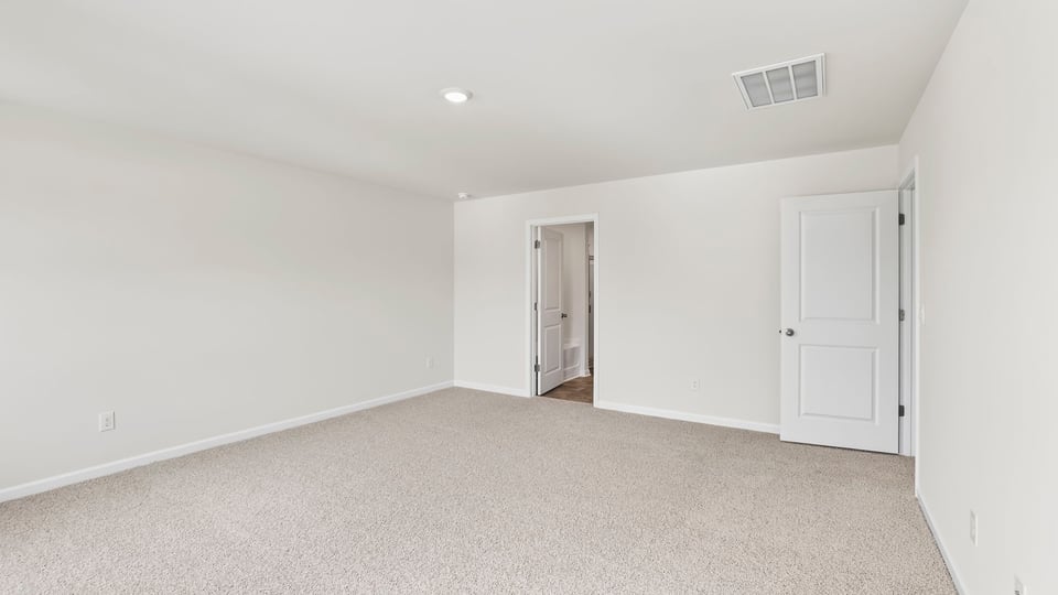 Primary bedroom with carpet and window.