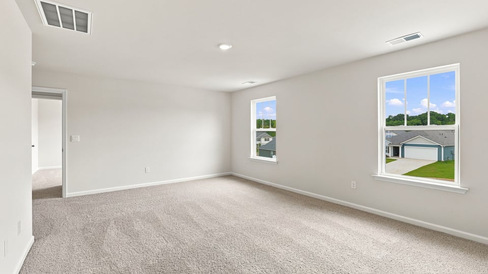 Primary bedroom with carpet and windows.