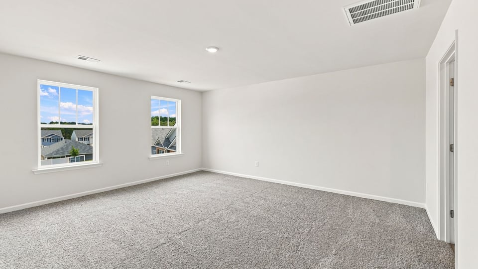 Primary bedroom with carpet and windows.