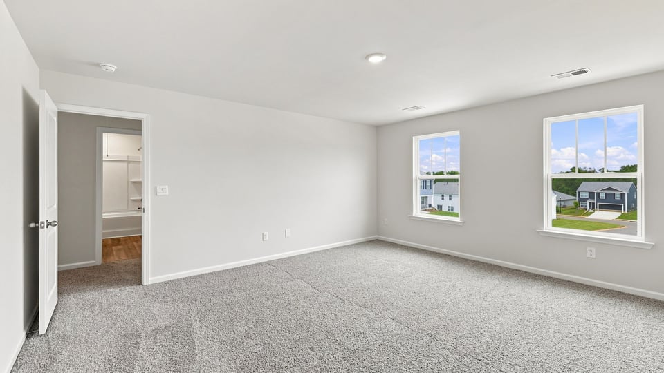 Primary bedroom with carpet and windows.
