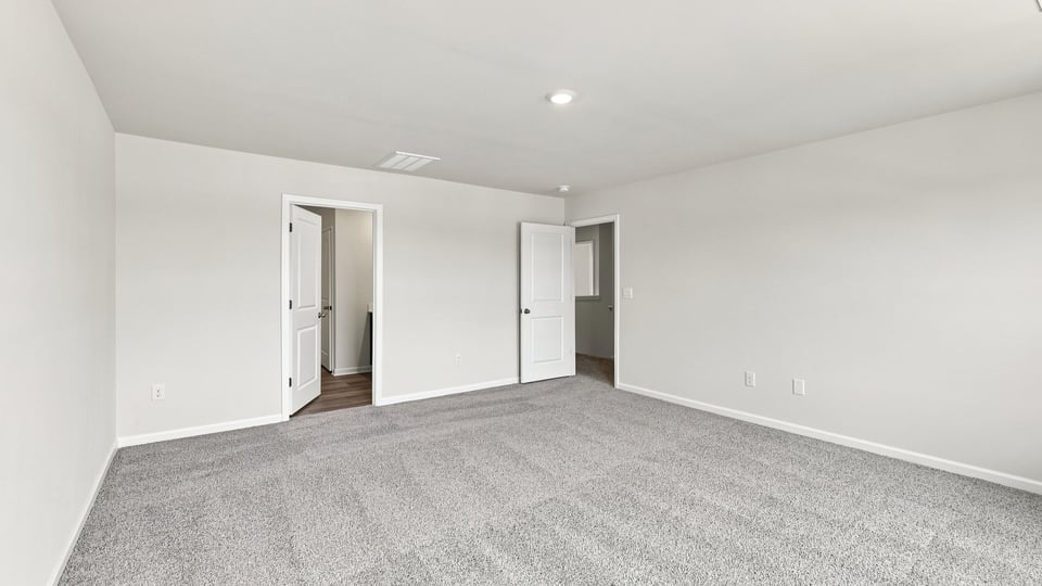 Primary bedroom with carpet and windows.