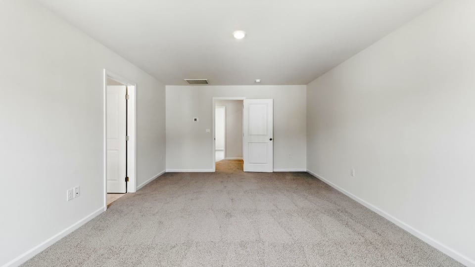 Primary bedroom with carpet and windows.