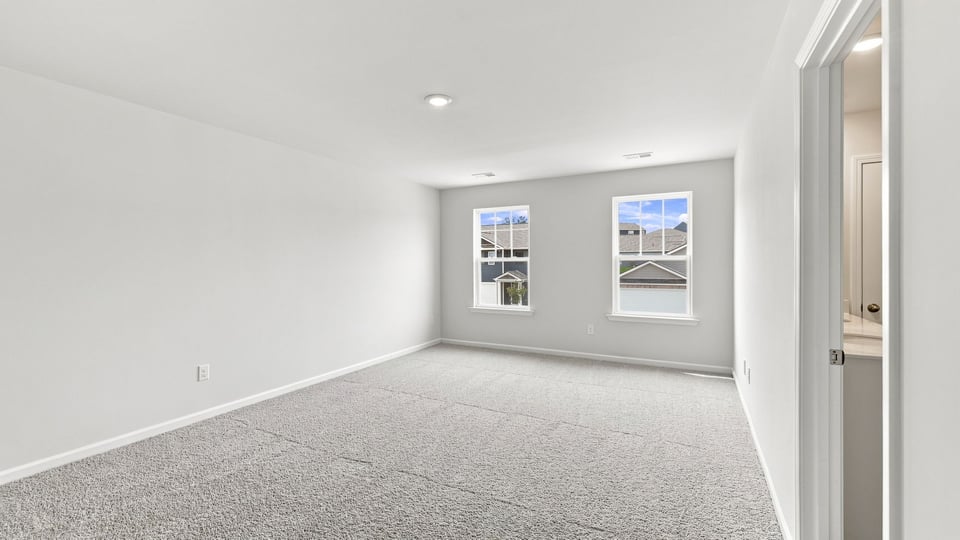 Primary bedroom with carpet and window.