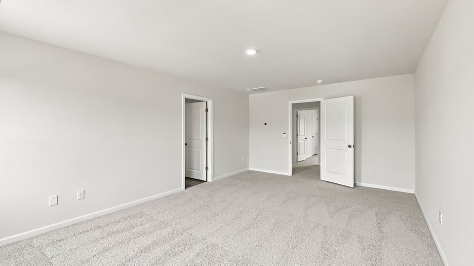 Primary bedroom with carpet and window.
