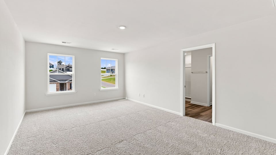 Primary bedroom with carpet and window.