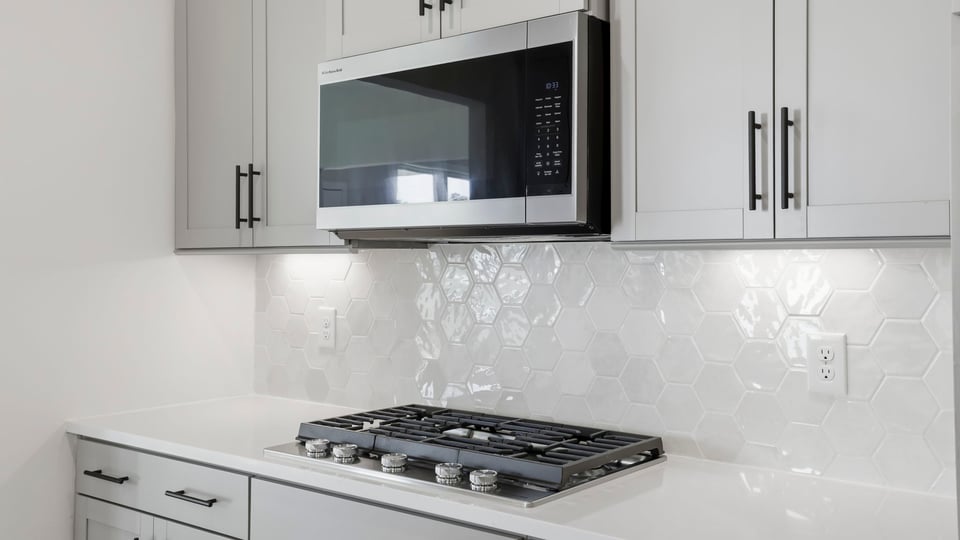 Kitchen and island with quartz countertops and stainless steel appliances.