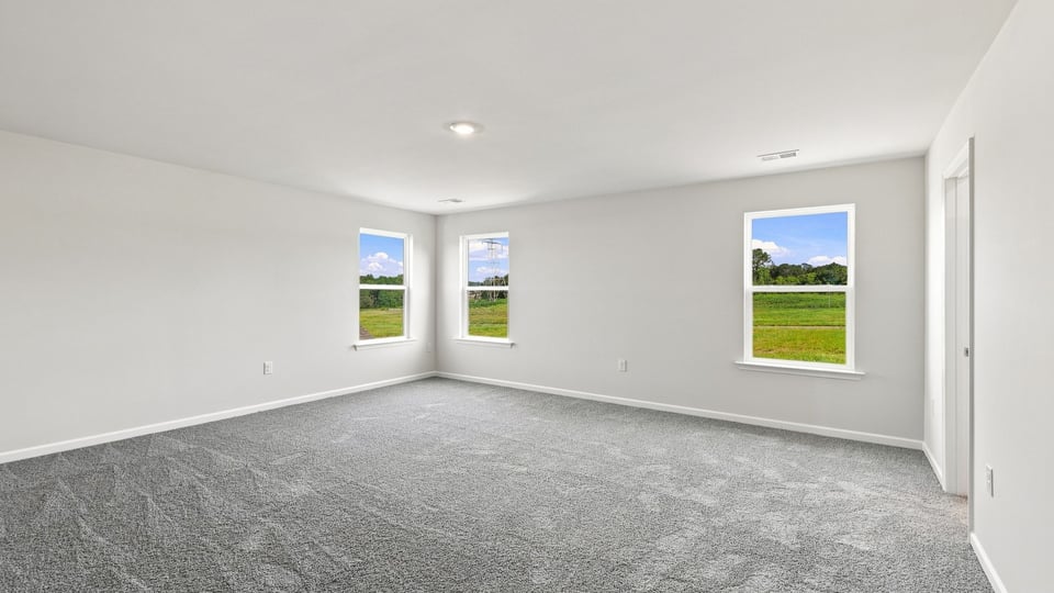 Primary bedroom with carpet and windows.