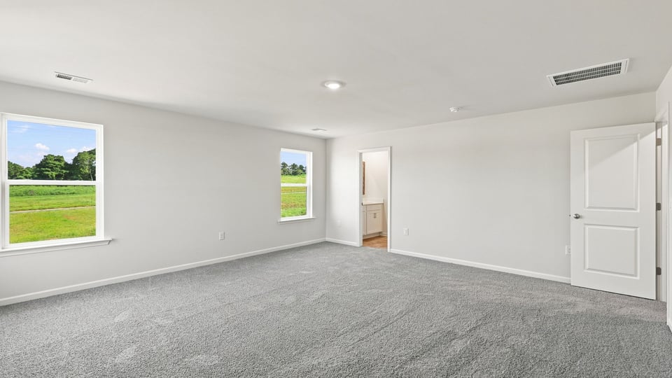 Primary bedroom with carpet and windows.