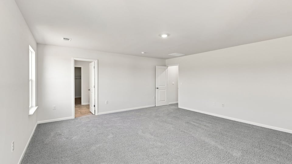 Primary bedroom with carpet and windows.