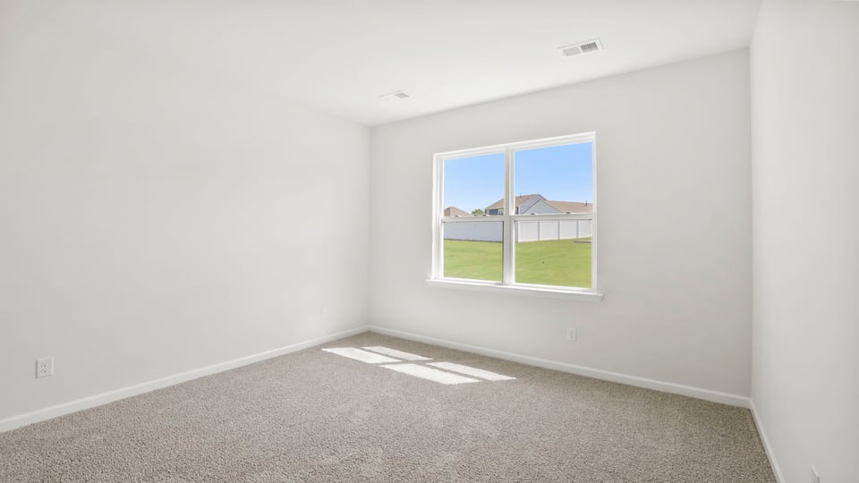 Primary bedroom with carpet and windows.
