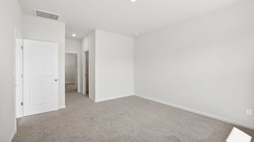 Primary bedroom with carpet and windows.