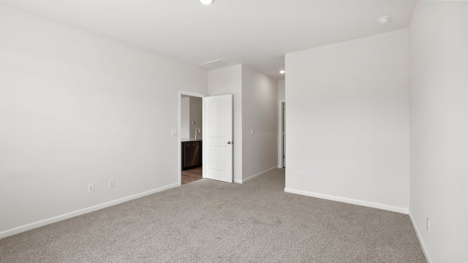 Primary bedroom with carpet and windows.