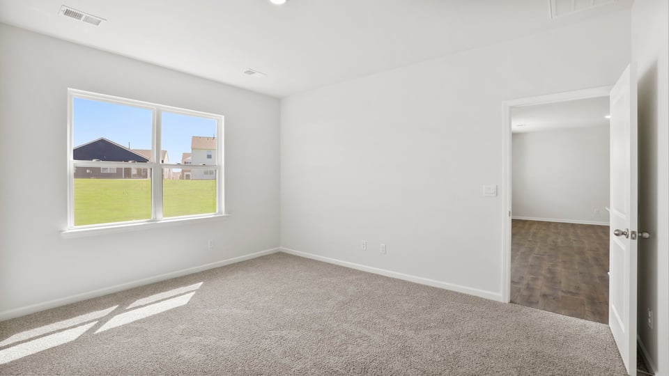 Primary bedroom with carpet and windows.