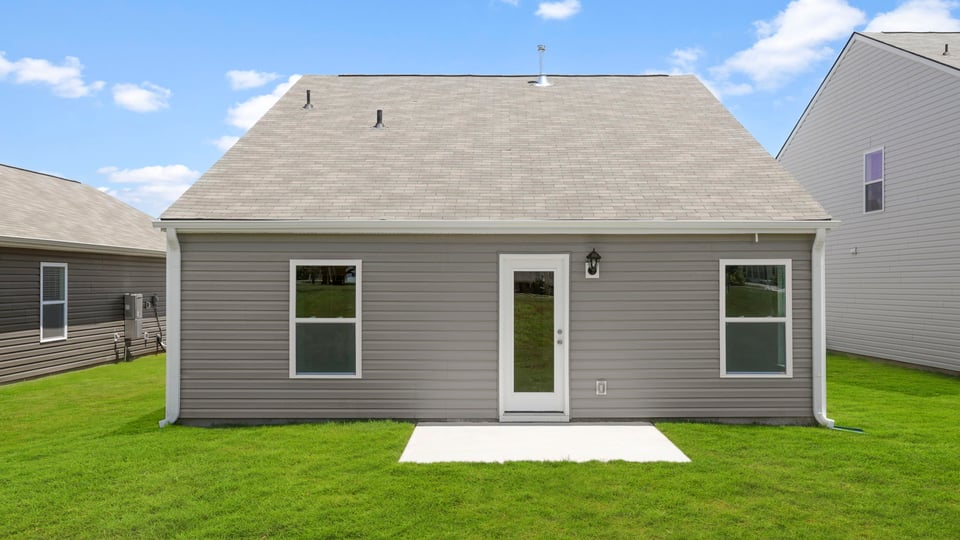 Large backyard of home with covered patio.