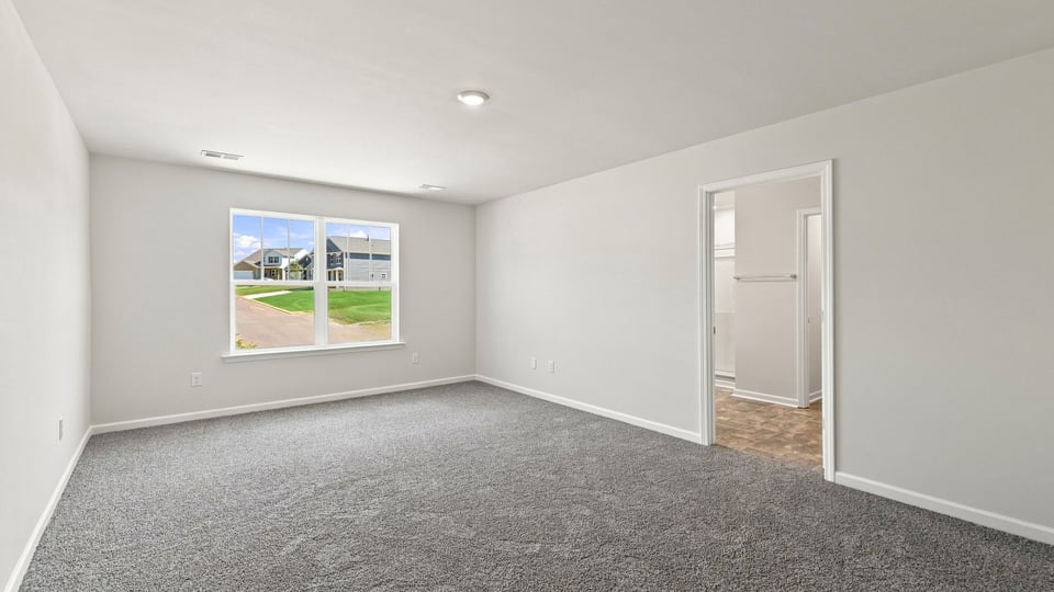 Primary bedroom with carpet and windows.