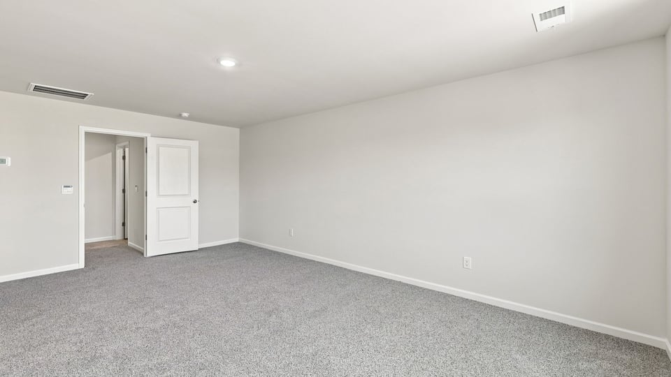 Primary bedroom with carpet and windows.