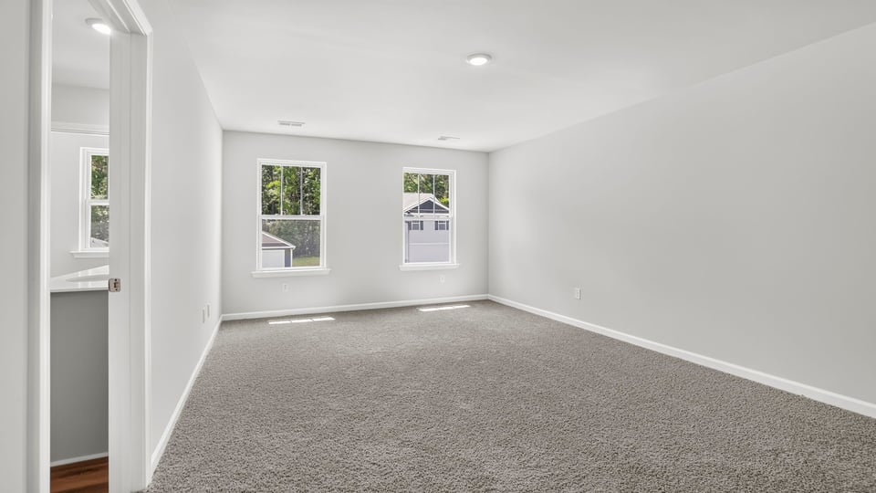 Primary bedroom with carpet and windows.