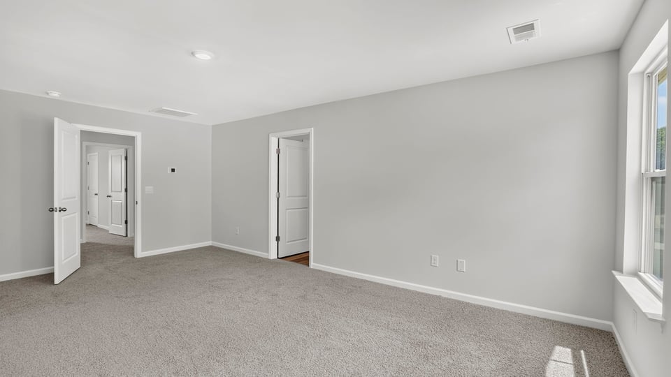Primary bedroom with carpet and windows.