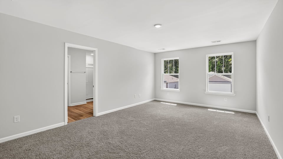 Primary bedroom with carpet and windows.