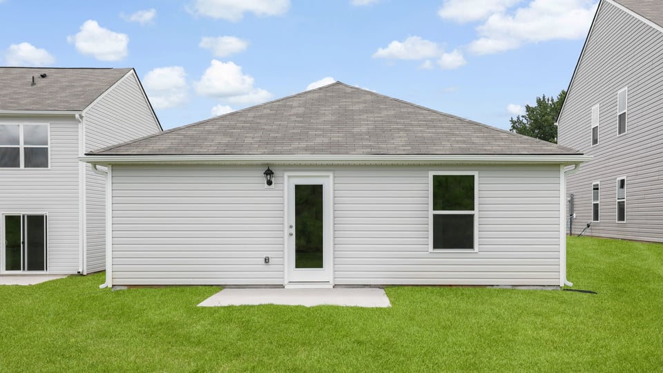 Large backyard of home with covered patio.