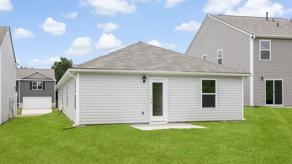 Large backyard of home with covered patio.