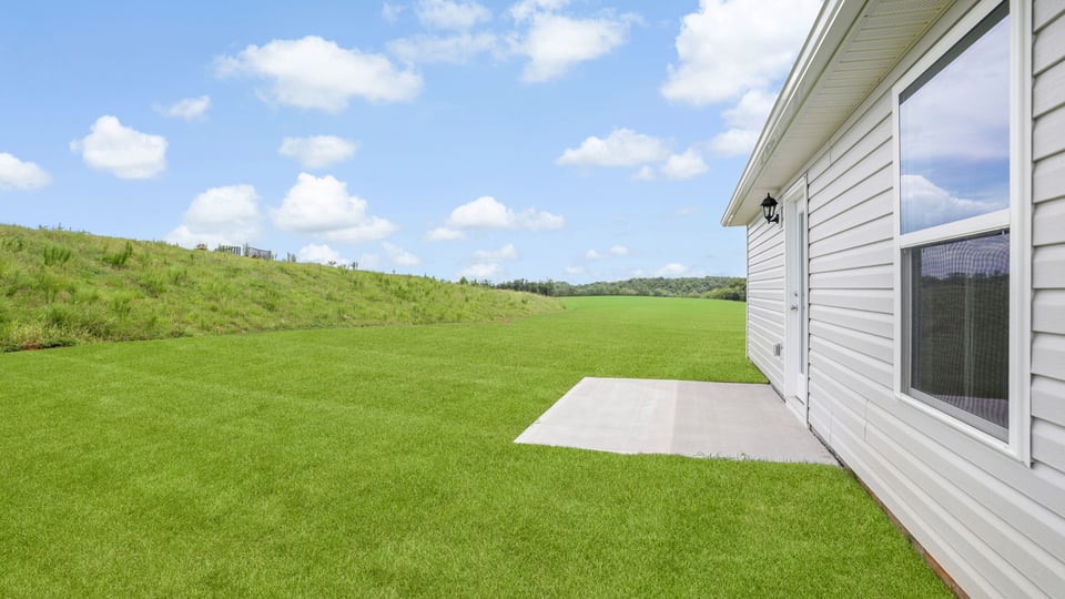 Large backyard of home with covered patio.