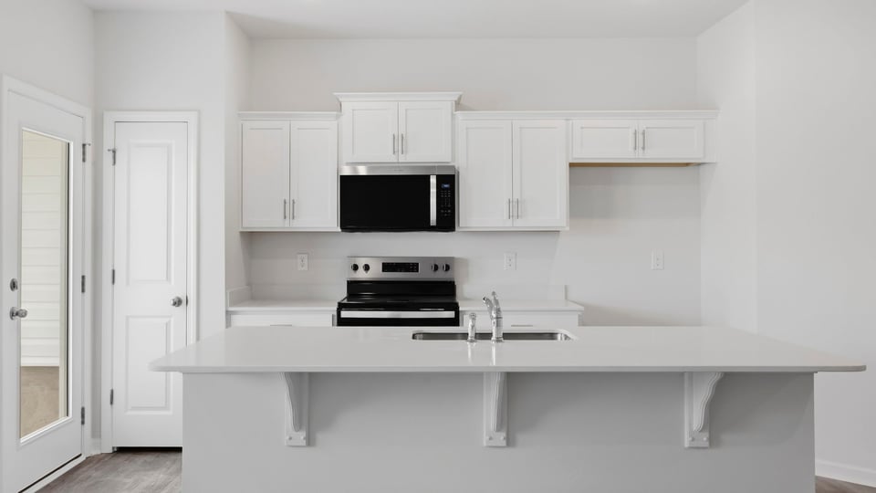 Kitchen and island with quartz countertops and stainless steel appliances.
